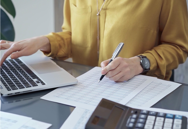 Person working with laptop and financial documents.